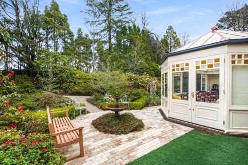 a garden with a white greenhouse and a patio at Bethany Manor Bed & Breakfast in Leura