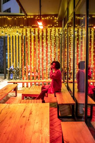 a woman sitting on a bench in a room with lights at Dialog Kokhta in Bakuriani