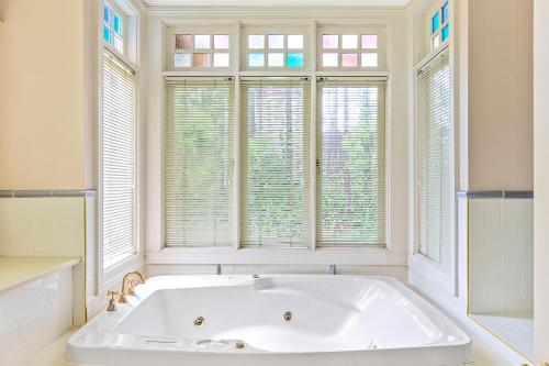baño con bañera blanca y ventanas en Bethany Manor B&B call them for Guaranteed Cheapest Price, en Leura