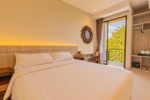 a bedroom with a large white bed and a balcony at The Baliem Hotel in Jimbaran