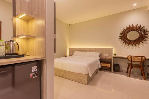 a bedroom with a bed and a table and a mirror at The Baliem Hotel in Jimbaran