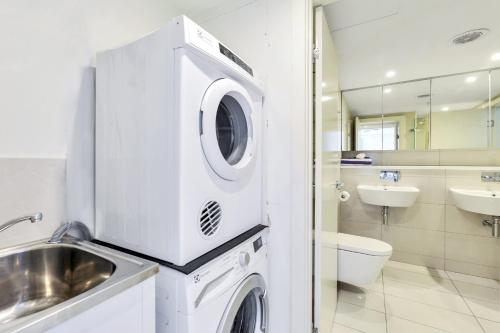 a bathroom with a washing machine and a sink at Darwin City Harbour views-Situated above the OAK Restaurant in Darwin