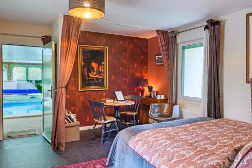 a bedroom with a bed and a table and a desk at Les Pierres Bleues in Saint-Coulitz
