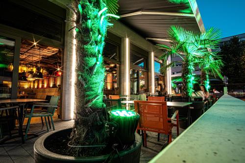 un restaurante con luces verdes en una mesa y palmeras en RiKu HOTEL Reutlingen, en Reutlingen