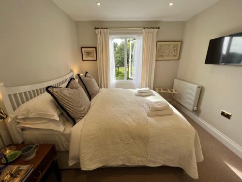 a bedroom with a large white bed with a window at Dell View - Charming & Cosy in Bentley