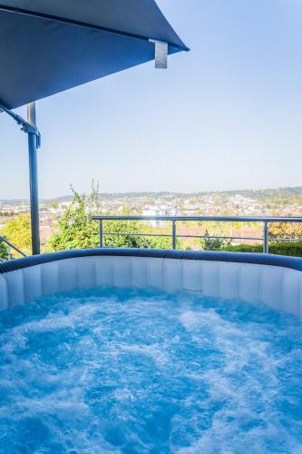 un bain à remous sur un balcon avec un parasol dans l'établissement Les chevrefeuilles Appartement en residence, à Brive-la-Gaillarde