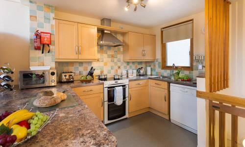 a kitchen with yellow cabinets and a bowl of fruit on the counter at Keswick Bridge Lodge Resort in Keswick