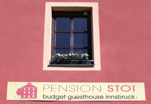 ein rosafarbenes Gebäude mit einem Fenster mit Blumen in einem Fensterkasten in der Unterkunft Pension Stoi budget guesthouse in Innsbruck