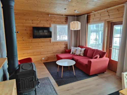 a living room with a red couch and a stove at Twin Peaks Urupää A Saariselkä in Saariselka