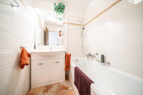 a bathroom with a white tub and a sink and a bath tub at 5401 Grosszuegige Dachgeschoss-Wohnung mit Parkettboden und Balkon - Moderne und helle Gestaltung in Vulpera