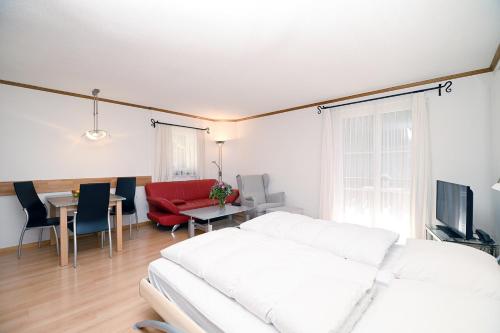 a living room with a white couch and a red chair at 6303 Komplett renoviertes und stilvolles Studio zum Wohlfuehlen in Vulpera