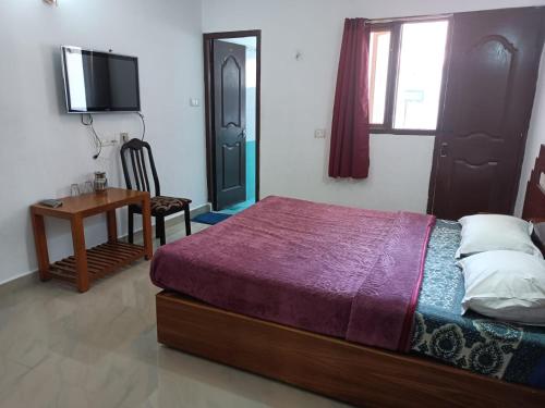 a bedroom with a bed and a desk and a television at Hill Heaven Home Stay in Kodaikānāl