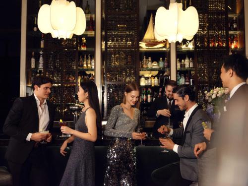 a group of people standing in a bar with drinks at The St. Regis Bangkok in Bangkok