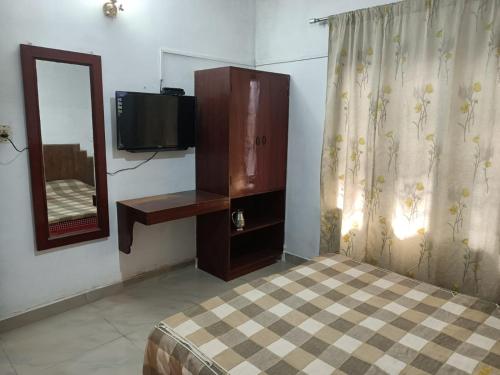 a bedroom with a bed and a tv and a mirror at Hill Heaven Home Stay in Kodaikānāl
