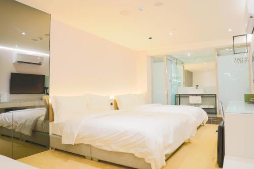 a bedroom with a large white bed and a television at Wonderwall Ximending in Taipei
