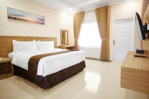 a hotel room with a large bed and a television at Agro Hotel Bintan in Telukbakau