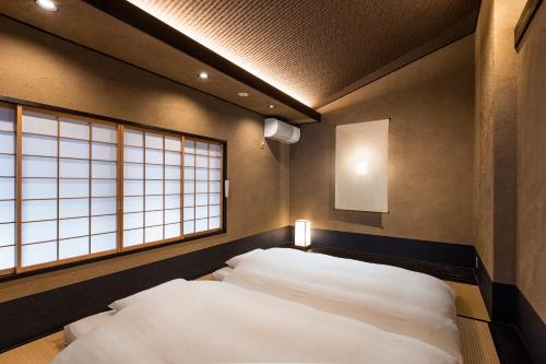 a bedroom with two beds and two windows at Rinn Premium Hiun in Kyoto