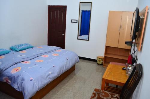 a bedroom with a bed and a table and a mirror at Hill Heaven Home Stay in Kodaikānāl
