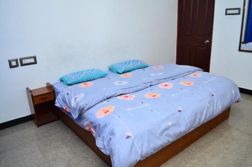 a bed with a blue comforter with flowers on it at Hill Heaven Home Stay in Kodaikānāl