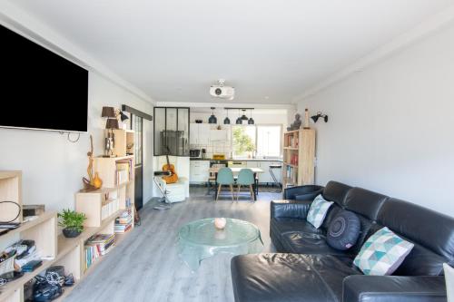 a living room with a leather couch and a table at Appartement avec balcon au Canal Saint-Martin in Paris