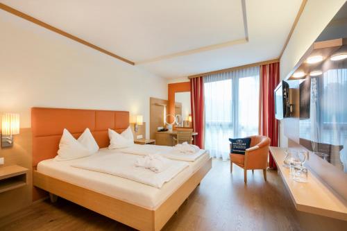 a hotel room with a large bed and a desk at Quellenhotel Heiltherme Bad Waltersdorf - 2-Thermenresort in Bad Waltersdorf