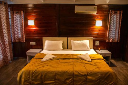 a large bed in a room with wooden walls at Cuba Patnem in Patnem