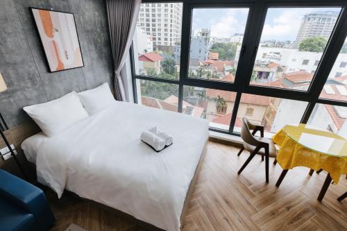 a bedroom with a white bed and a table and window at Westlake Emerald Suites in Hanoi