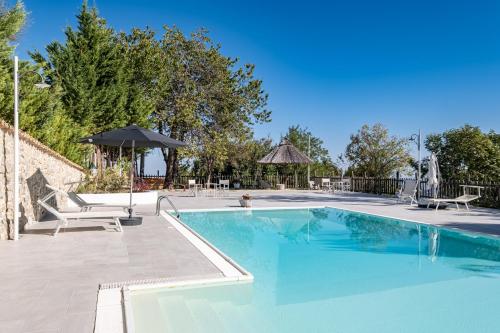 a swimming pool with two chairs and an umbrella at Borgo Majella by Rentbeat in Abbateggio