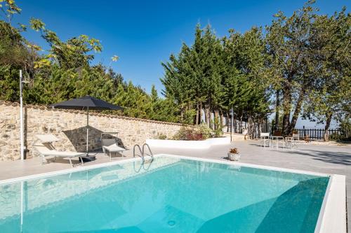 a swimming pool with chairs and an umbrella next to a stone wall at Borgo Majella by Rentbeat in Abbateggio