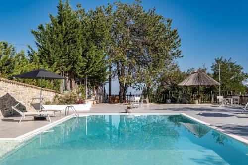 a swimming pool with two chairs and an umbrella at Borgo Majella by Rentbeat in Abbateggio