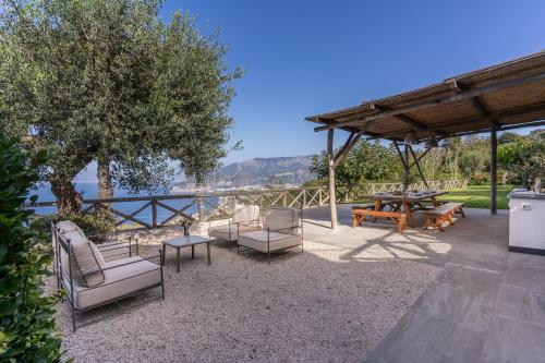 an outdoor patio with chairs and a table and a picnic table at Villa Giulia Boutique Views Pool and Guest Services by Feeling Italy in Sorrento