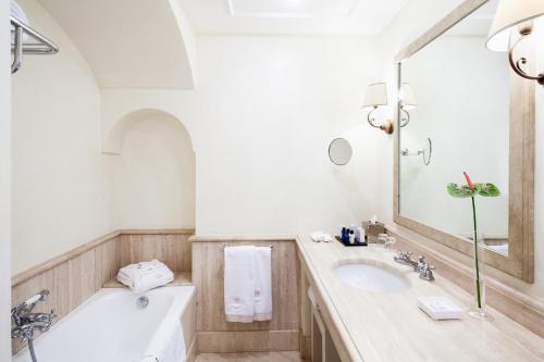 a bathroom with a tub and a sink and a mirror at Jumeirah Capri Palace in Anacapri