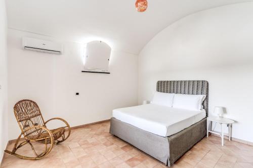 a white bedroom with a bed and a chair at Villa Giulia Boutique Views Pool and Guest Services by Feeling Italy in Sorrento