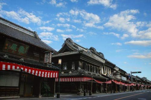 un edificio con banderas rojas y blancas en una calle en 小江戸川越ハウス en Kawagoe