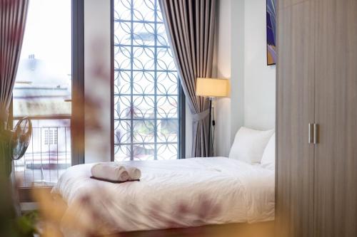 a bedroom with a white bed with a window at Westlake Emerald Suites in Hanoi