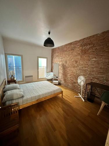 une chambre avec un lit et un mur de briques dans l'établissement Spacieux Appartement 2 Chambres Plein Cœur de Perpignan, à Perpignan