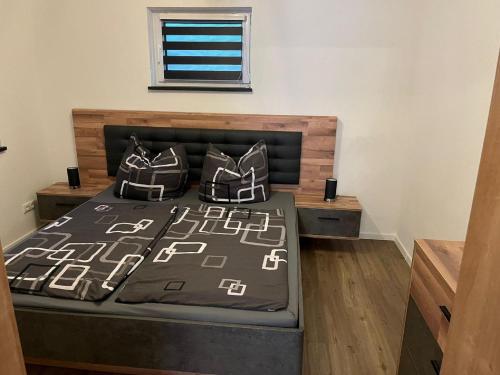 1 dormitorio con 1 cama con almohadas blancas y negras en Bayerwaldapartment, en Viechtach