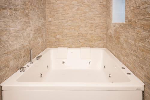 a white bath tub in a bathroom with a brick wall at Qu4ttro I Domus47 Pompei in Pompei