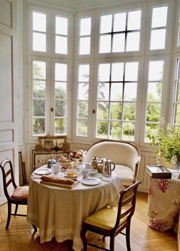 une salle à manger avec une table, des chaises et des fenêtres dans l'établissement Villa du Châtelet, à Choisy-au-Bac