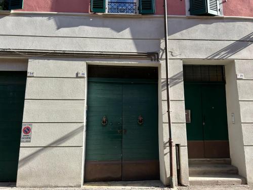 two green doors on the side of a building at Residence Le due Corti in Imola