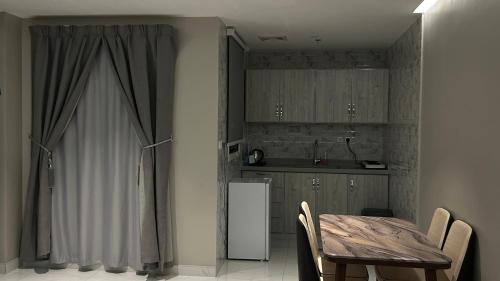 a kitchen with a table and a white refrigerator at لاقونا للشقق المخدومة in Al Ahsa