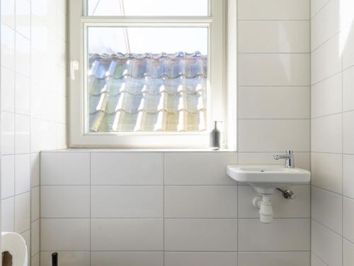 een witte badkamer met een wastafel en een raam bij 2 adjacent apartments in the heart of Sneek in Sneek