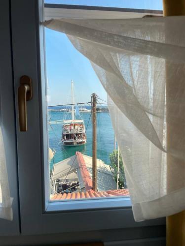 a window with a view of a boat in the water at Manus Dei Exclusive Suites in Pythagoreio