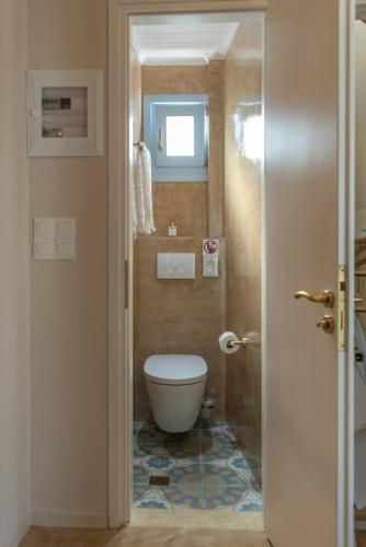 a small bathroom with a toilet and a window at Manus Dei Exclusive Suites in Pythagoreio