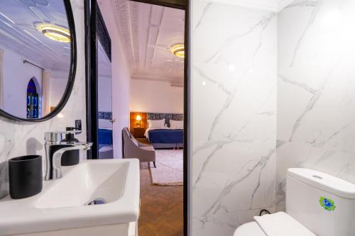 La salle de bains blanche est pourvue d'un lavabo et d'un miroir. dans l'établissement The Grand Riad and Spa, à Marrakech