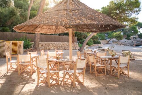 a group of tables and chairs under a large umbrella at Hotel Cala Dor - Adults Only in Cala d´Or