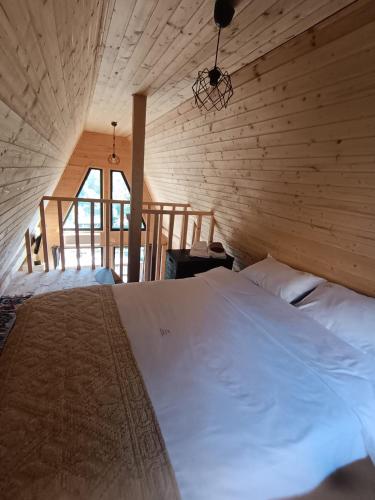 1 dormitorio con 1 cama blanca grande en una pared de madera en CarpatinA Rustic House, en Runcu