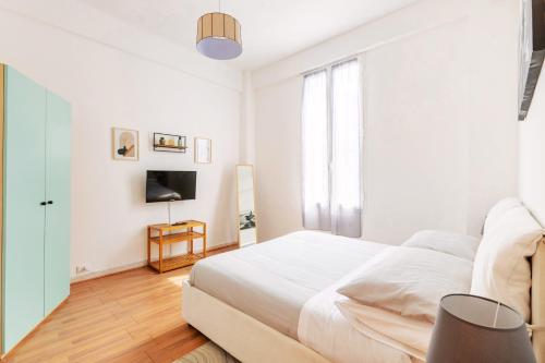 ein weißes Schlafzimmer mit einem Bett und einem Fernseher in der Unterkunft [Mare - Ciclabile] Giardino e Parcheggio gratuito in Sanremo