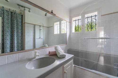 W białej łazience znajduje się umywalka i lustro. w obiekcie Vacances révées au Pin Parasol w mieście Le Thor