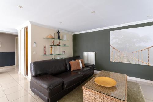 a living room with a black leather couch at Vacances révées au Pin Parasol in Le Thor